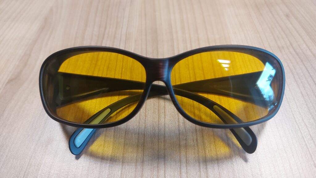 Photo d'une paire de lunettes avec des verres médicaux filtrant, posée sur un table en bois.